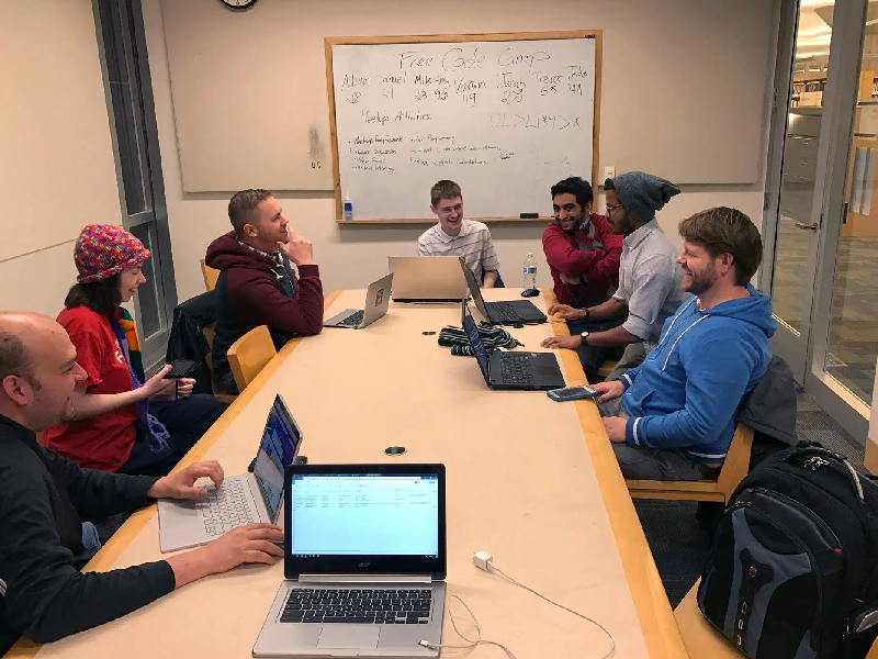 The members of Free Code Camp Twin Cities sitting around a table learning about Front End Web Development